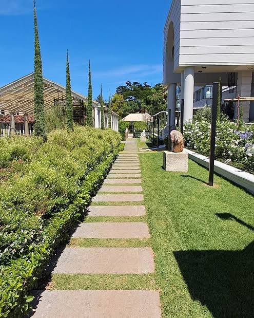Stepping-stone garden path at Siyekhaya Estate, lined with cypress trees and flowering beds